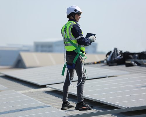 engineers installing solar panels on roof. Male engineers walking along rows of photovoltaic panels